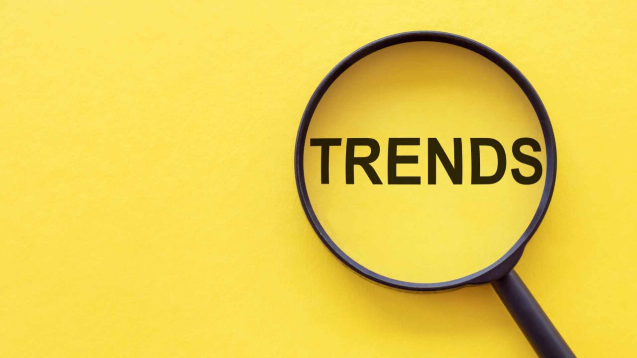 TRENDS text written on magnifier glasses, on yellow background. Main trend of changing something. Popular and relevant topics. New trends in business. Recent and latest trend. Evaluation methods.