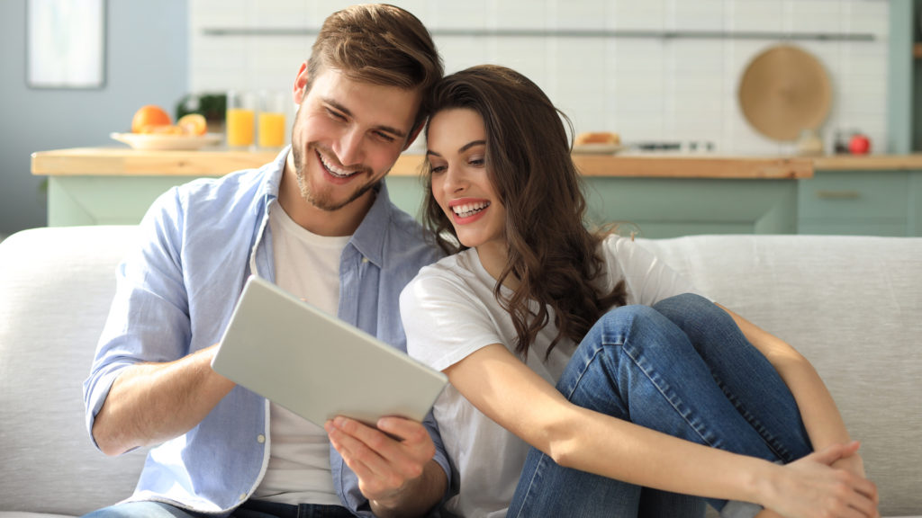 Couple looking at tablet, enjoying great customer service through transactional SMS and email